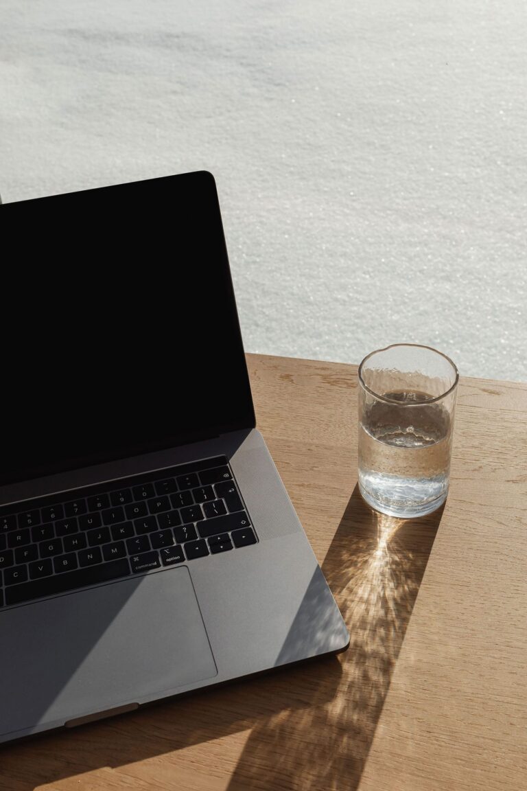 photo d'ordinateur posé sur un bureau avec un verre d'eau.